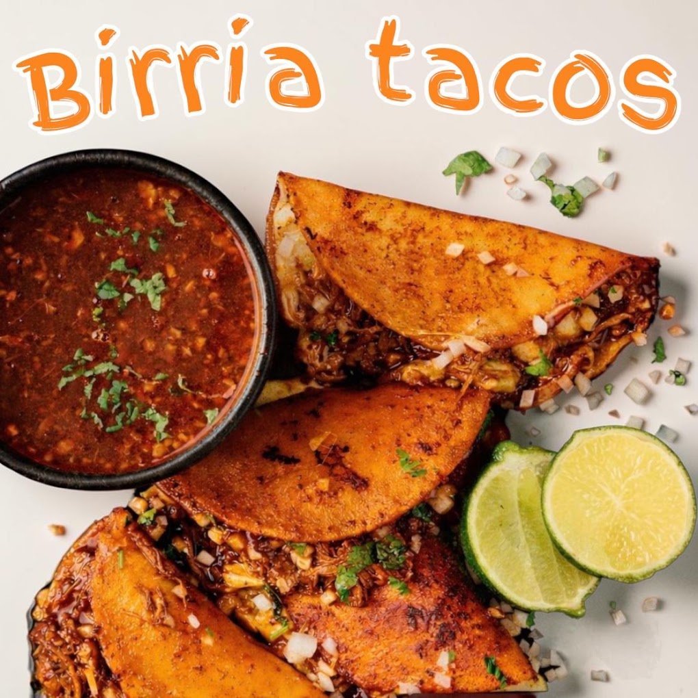 Three crispy birria tacos on a plate with red sauce, diced onions, cilantro, and lime wedges