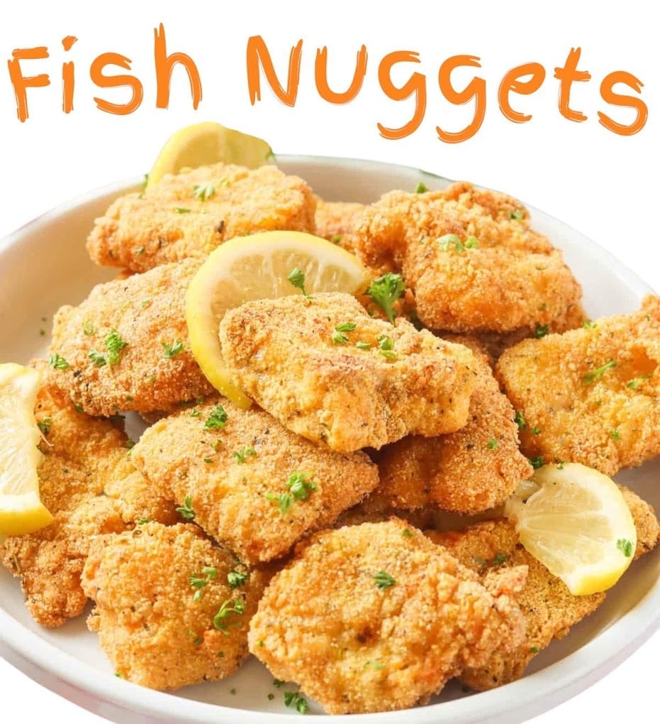 Golden-fried fish nuggets on a white plate garnished with lemon slices and fresh parsley